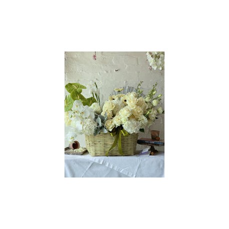 Mara, arreglo floral en canasta en tonos blancos.